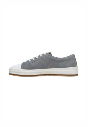 Szare zamszowe sneakersy z białym gumowym czubkiem i podeszwą, z białymi sznurówkami oraz brązowym akcentem na pięcie. Gładka tekstura i casualowy styl.