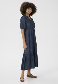 Denim midi-klänning med korta puffärmar, knappstängning fram, samlad midja och vågig nederkant. Bärs med lägenheter i leopardmönster.
