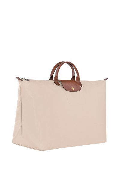 Beige fabric tote bag with a structured shape, brown leather accents, dual top handles, and a zip closure. Flat sides and no visible patterns.