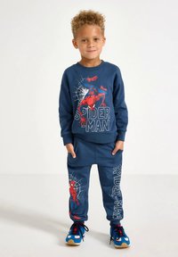 Blå bomullsgenser og matchende joggebukser med Spider-Man-grafikk, lange ermer og elastisk midjebånd med sidelommer.