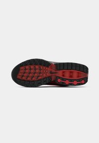 Black and red sneaker sole featuring a textured rubber design with visible tread patterns and distinctive red accents.