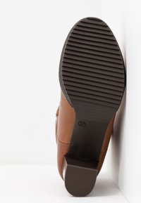 Semelle de chaussure en cuir marron avec texture rainurée, design plat, marquage taille 37 et un léger talon. Le fond est blanc uni.