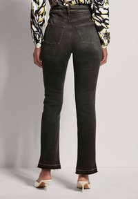 Hoge taille donkergrijze denim jeans met een rechte pijp, rafelige zoom en twee achterzakken. Draag je met lichtgekleurde haksandalen.