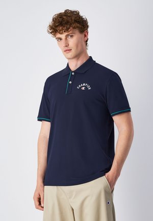 Polo shirt marine en tissu doux, avec un logo sur la poitrine, un col à deux boutons et des accents teal contrastants au niveau du col et des manches.