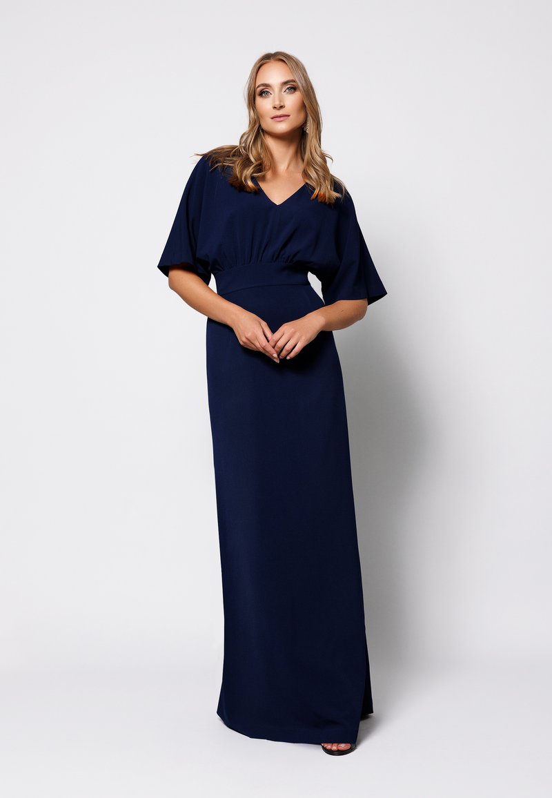 Granatowa sukienka maxi z krótkimi, szerokimi rękawami, dekoltem w kształcie litery V i dopasowanym pasem. Materiał jest gładki z delikatnym połyskiem i bez wzorów.