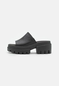 Sandali a piattaforma neri in pelle liscia, con punta chiusa, suola spessa con dettagli a intaglio e logo in rilievo.