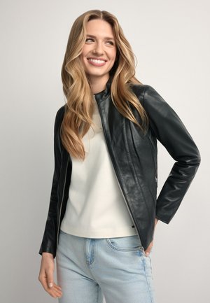 Czarna skórzana kurtka zapinana na zamek z przodu, z okrągłym dekoltem i dopasowanym krojem, zestawiona z białym topem i jasnoniebieskimi dżinsami.