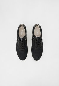 Baskets en suède noir avec un accent en cuir lisse, dotées de lacets et de zips sur les côtés, conçues pour le confort et la polyvalence.