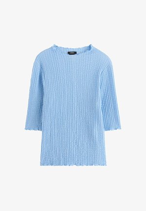 Lyseblå, ribbet striktrøje med rund udskæring og ærmer til albuen. Dækkende kant og teksturdetaljer i hele stoffet.