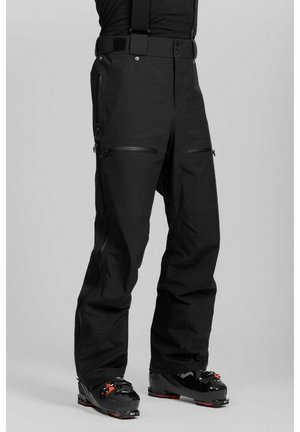 Mustat vedenpitävät hiihtohousut olkaimilla, jotka on puettu hiihtokenkien päälle. Housuissa on etu- ja sivutaskut vetoketjuilla sekä vahvistetut nilkat.