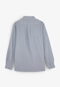 Camicetta grigia chiara a maniche lunghe con colletto a bottoni, un solo plissetto sul retro e polsini abbottonati. Tessuto liscio e morbido con dettagli di design minimi.