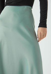 Voogav teal seelik, mis on valmistatud siledast kangast, esitades kõrge vö�ökoha disaini ja kerge sära. Rikkalikult mustrit rõhutav.