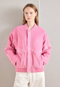 Rosa kordfløyelsjakke med en ribbet tekstur, elastisk liv, trykknapplukking, og to frontlommer. Avsluttet med en ståkrage.