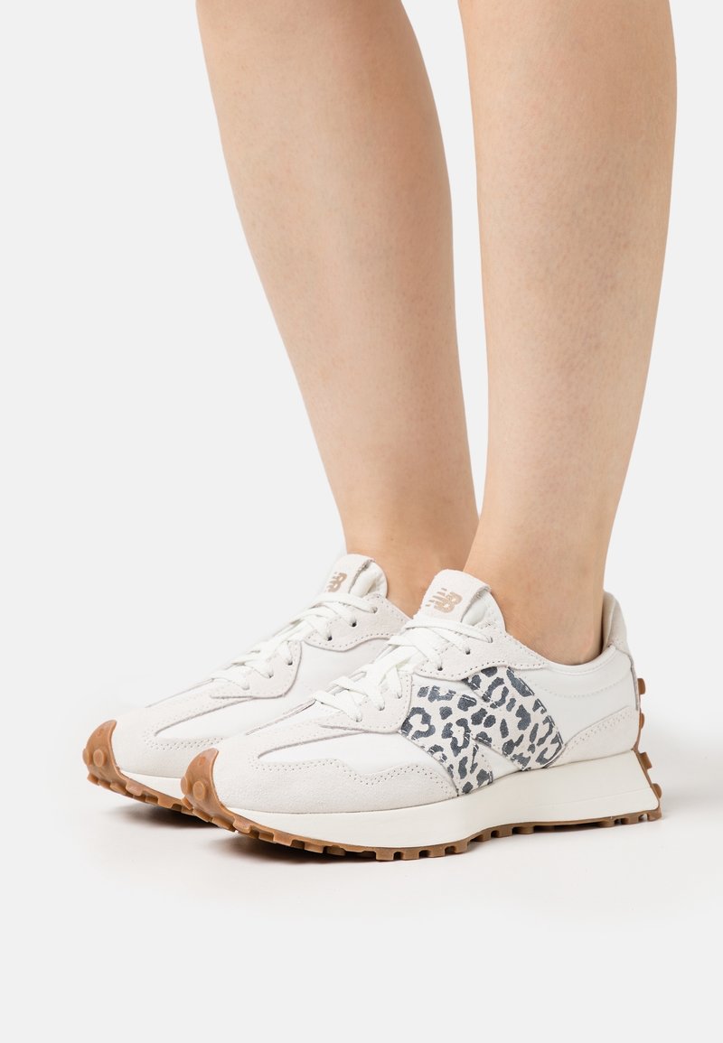 Des chaussures de sport blanches avec un accent en imprimé léopard texturé sur le côté et une semelle en caoutchouc marron. Conçues avec des lacets et un col rembourré.