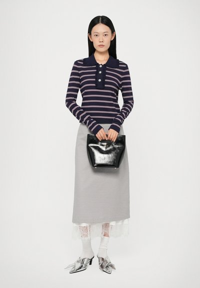 Gestreiftes marineblaues Langarm-Polo mit einem rüschierten Kragen, grauer Rock mit Spitzenbesatz, schwarze Handtasche und metallische spitz zulaufende Schuhe.