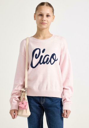 Hellrosa Pullover mit "Ciao" in dunkelblauer Schrift, mit gerippten Bündchen und Saum. Kombiniert mit dunkelblauen Jeans und einer kleinen beigen Tasche mit einem pinken Akzent.
