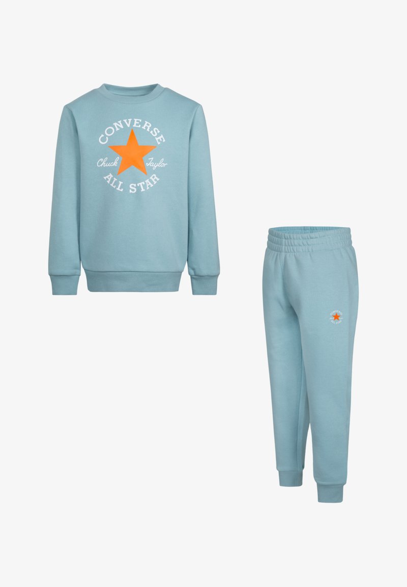 Világoskék pulóver és hozzá illő pamut nadrág, középen narancssárga csillaglogóval és fehér felirattal. A pulóver bordázott mandzsettával rendelkezik.