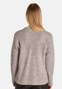 Grijze gebreide trui met diagonale ribbels en metallic draadaccenten, met een relaxte pasvorm en verlaagde schouders. Achteraanzicht weergegeven.