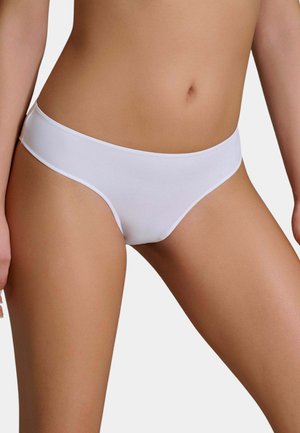 Donna che indossa slip bikini bianchi a vita bassa, mostrata dalla vita alla parte superiore delle cosce su sfondo neutro.