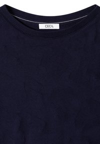 Pull en maille bleu marine foncé avec un motif texturé subtil et une encolure ronde côtelée avec une étiquette blanche indiquant "CECIL" à l'intérieur du col.