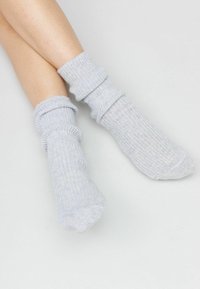 Ljust grå ribbade strumpor har en slouchy design med rullade muddar, tillverkade av ett mjukt, texturerat tyg som är lämpligt för vardagsbruk.