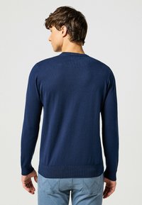 Maglione lavorato a maglia blu navy con maniche lunghe, collo rotondo, polsini e orlo a costine; texture liscia con un motivo uniforme.