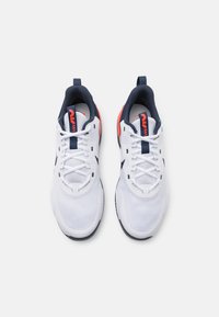 Białe buty sportowe z teksturowanym wzorem, granatowymi akcentami i koralowymi detalami. Wyposażone w sznurowane zapięcie oraz pętelkę na pięcie.