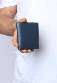Navy leather wallet with stitched edges, features a triangular cutout pattern, logo embossed on the bottom right, held in a hand.