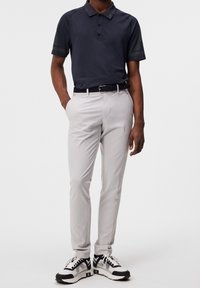 Námořnická polokošile s krátkými rukávy, světle šedé slim-fit kalhoty a černobílé sneakers s síťovinovými akcenty. Opasek je pletený z námořnického materiálu.