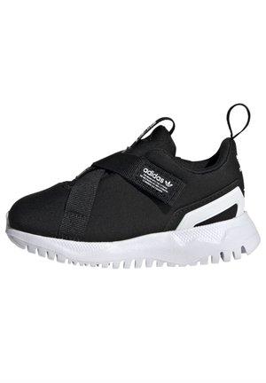 Czarny sneaker Adidas z białą podeszwą, bezsznurowym fasonem, elastycznymi paskami i pętelką na pięcie na białym tle.