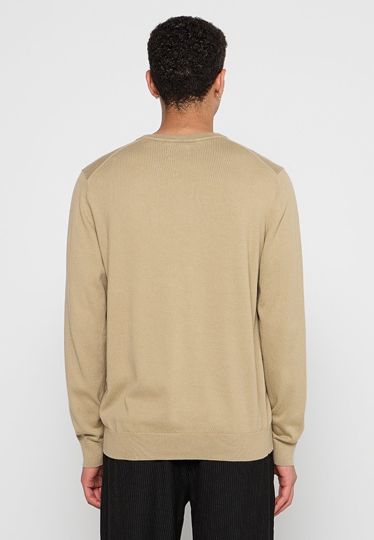 Beige gestrickter Pullover mit langen Ärmeln, rundem Halsauschnitt, gerippter Textur und taillierter Passform. Keine sichtbaren Muster oder Akzente.