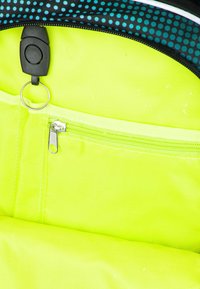 Světle žlutý interiér batohu s zipovou kapsou, vybavenou černým táhlem a stříbrným zipem. Hladká textura s viditelným švem.