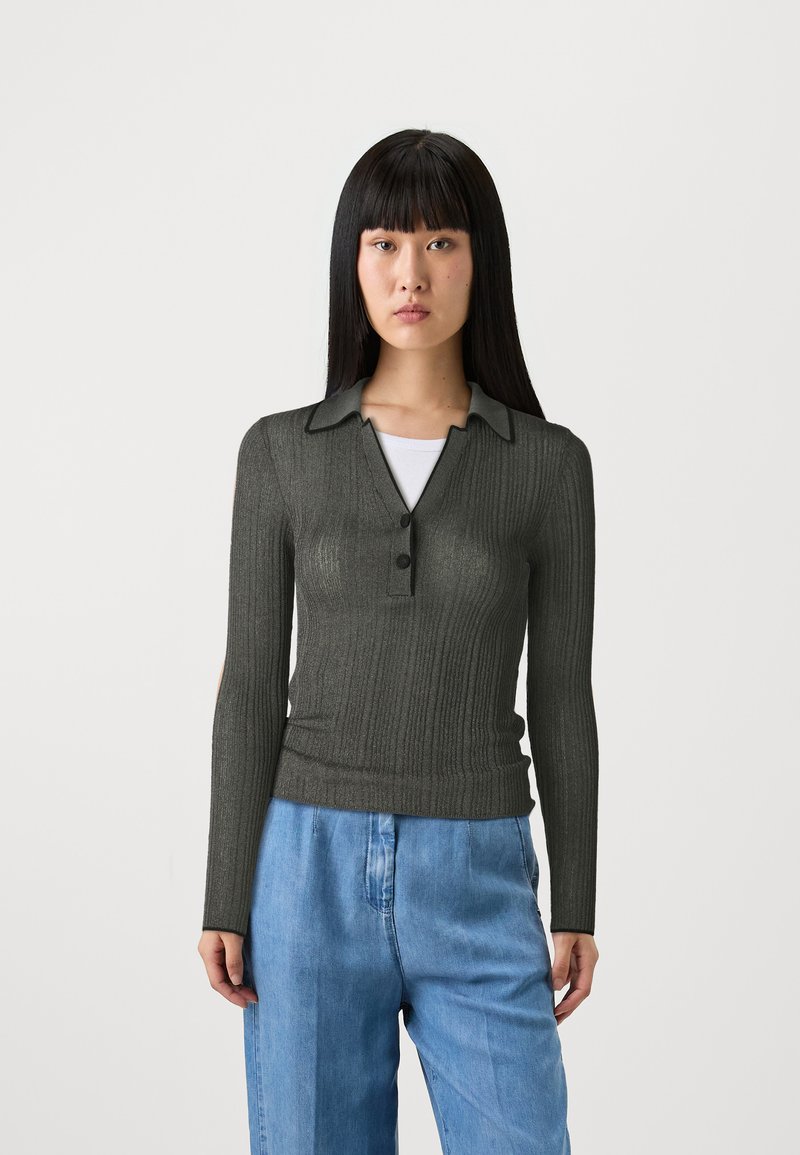Dunkelgrünes, geripptes Langarm-Polohemd mit Kragen und einer Dreiknopf-Leiste, kombiniert mit hellblauen, locker sitzenden Jeans.