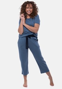 Blauwe loungewear set met een korte mouwen top en cropped broek, voorzien van een trekkoord in de taille en een relaxte pasvorm. Zachte, gladde textuur.