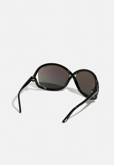 Occhiali da sole neri con forma ovale allungata, lenti scure sfumate e montatura nera in plastica elegante e curvata con sottili accenti dorati.