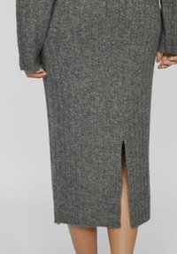 Vestido de punto acanalado gris que presenta una longitud a media pantorrilla y una abertura trasera que facilita el movimiento. La textura de la tela es suave con un sutil brillo.