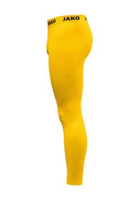 Leggings giali con una texture liscia, caratterizzati da un logo "JAKO" nero sulla vita. Il design è aderente e slanciato.