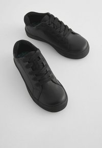 Baskets en cuir noir avec une texture lisse, dotées d'un bout arrondi, d'une semelle en caoutchouc noir plate et de lacets tissés pour un maintien sécurisé.