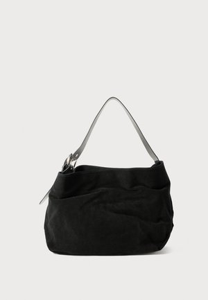 Black suede bag with a soft, slouchy design. Features a thin, smooth leather shoulder strap and subtle stitching details.
