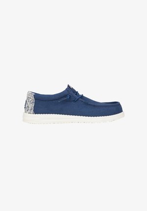 Marineblauwe canvas schoenen met een gestructureerde witte zool, voorzien van een ronde neus en vetersluiting, benadrukt door een geblokte achterpaneel.