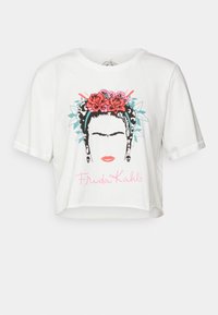 Bílý zkrácený tričko s grafikou ženské tváře s květinovými akcenty, výraznými obrysy a textem "Frida Kahlo" v růžové barvě.