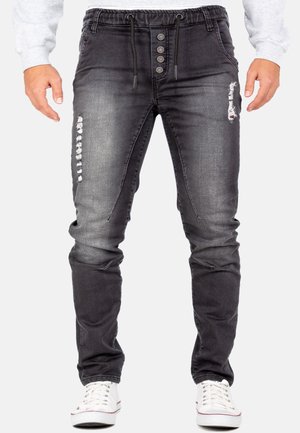Zwarte denim joggerbroek met een trekkoord taille, vijf knopen bij de gulp, versleten accenten en een slim fit ontwerp.