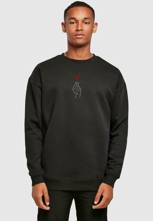 Black sweatshirt with a crew neckline, featuring a white outline of a hand and a small red heart graphic on the front. Soft fabric.
