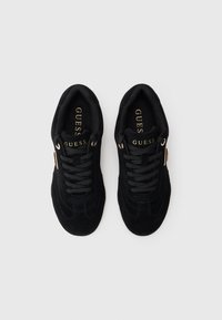 Crne tenisice od antilopa s zaobljenim vrhom, vezanjem na vezice, teksturiranom površinom, zlatnim logotipom na jeziku i srebrnim rupicama za vezice.