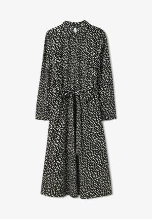 Robe à motifs en noir et blanc avec un col, des manches longues et une ceinture à la taille. Tissu léger avec un design fluide.