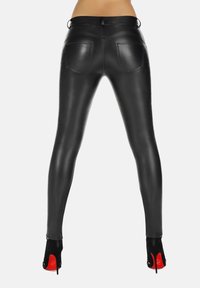 Czarne legginsy z eko skóry z wysokim pasem, o dopasowanym kroju i dwoma tylnymi kieszeniami. Zestawione z czarnymi butami na wysokim obcasie.