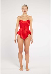 Red satin romper with a relaxed fit, featuring thin shoulder straps and a belted waist. The fabric has a smooth, glossy texture.
