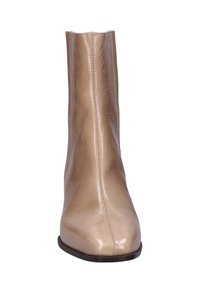 Beige enkelboot met een slanke, glanzende leren textuur. Het ontwerp heeft een rechte schacht, een ronde neus en zichtbare stiksels langs de zijkanten.