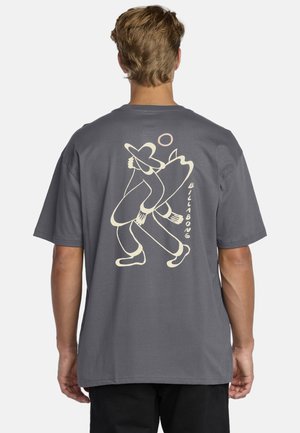 Camiseta de manga corta gris con un gran gráfico beige de una persona sosteniendo una tabla de surf, con bordes redondeados y un ajuste casual.