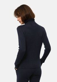 Pull à col cheminée marine en tissu tricoté doux et texturé. Design ajusté avec des manches longues et un col côtelé, présentant un dos lisse et épuré.